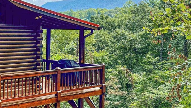 A wooden cabin with a balcony overlooking a forested mountain area. - Ogana Ridge Getaways (Ellijay)