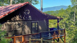A log cabin with a metal roof, a chimney, and a wooden deck. - Ogana Ridge Getaways (Ellijay)