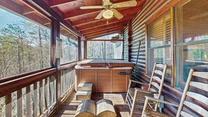 A log cabin with a wooden deck, a ceiling fan, and a view of the forest. - Wonderland Ellijay Stay (Ellijay)