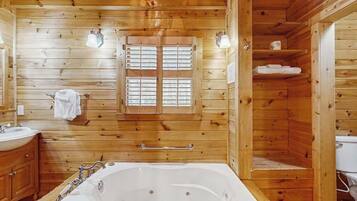 L’intérieur d’un chalet en bois, avec une grande baignoire, des murs en bois et une fenêtre avec des volets.