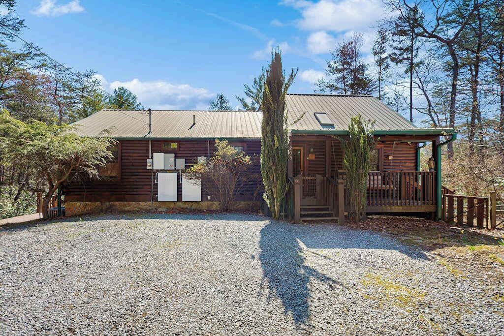 Eine rustikale Holzhütte mit Kiesweg, Holzfassade und einer Veranda.