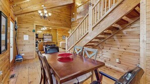 A wooden interior with a dining table, chairs, a staircase, and a kitchen area. - Wonderland Ellijay Stay (Ellijay)