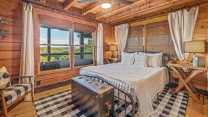 Quarto de cabana de madeira com cama, cortinas, janela e ventilador de teto.