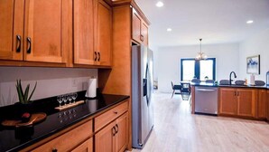 Eine moderne Küche mit Holzausstattung, einem Edelstahlkühlschrank und einem Essbereich mit Tisch und Stühlen.