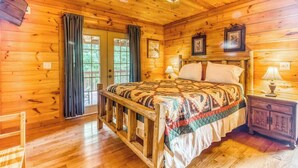 Un dormitorio de cabaña de madera con cama, mesita de noche y ventilador de techo.