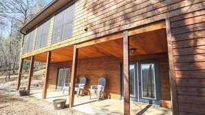 Eine Holzhütte mit überdachter Veranda, zwei Türen und zwei Fenstern.