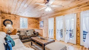 Ein Holzinterieur mit einer Couch, einem Couchtisch und einem gemusterten Hocker.