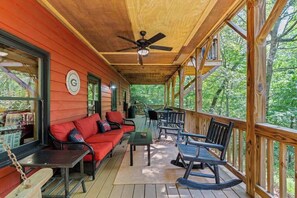 A covered porch with a ceiling fan, a red sofa, and rocking chairs. - It's a Wonderful Life (Sautee Nacoochee)