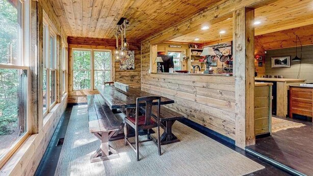 A wooden cabin interior with a dining area, kitchen, and large windows. - It's a Wonderful Life (Sautee Nacoochee)