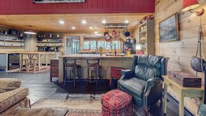 A cozy cabin interior with a kitchen, dining area, and a living room with a leather sofa and ottoman. - It's a Wonderful Life (Sautee Nacoochee)