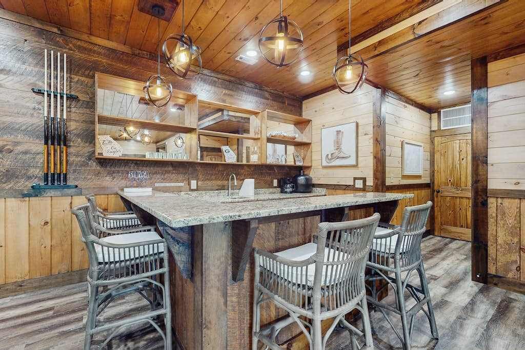 A wooden interior with a bar area, wicker chairs, and pendant lighting.