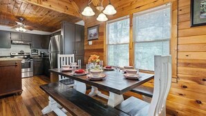 A wooden cabin interior with a kitchen, dining table, and benches. - Mountain Rivers Lodge (Mineral Bluff)