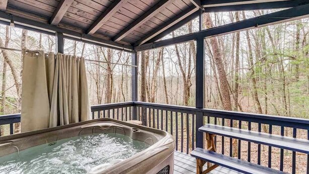 Ein Whirlpool auf einer Holzterrasse mit Blick auf Bäume.