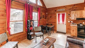 Ein Interieur einer Holzhütte mit Essbereich, Küche und einem Schild mit der Aufschrift 'HAPPY CAMPER'.