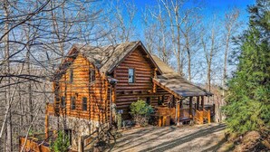 A log cabin with a porch, surrounded by trees. - Lakeview Manor Cabin (Blue Ridge)
