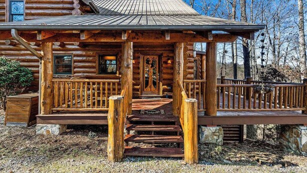 A log cabin with a porch, wooden steps, and a stone foundation. - Lakeview Manor Cabin (Blue Ridge)
