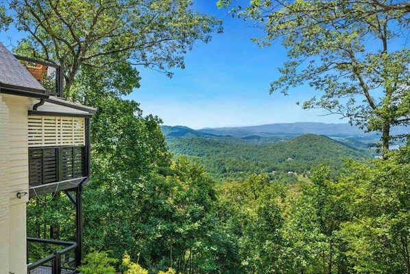 A building with a balcony overlooking a forested valley. - Ivy Mountain Top Stay (Hiawassee)