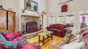 Ein großzügiges Wohnzimmer mit Kamin, gemusterten Sofas und einem Kaminverkleidung aus Stein.