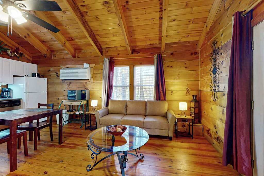 Een houten cabin inrichting met een bank, eettafel en keukenhoek.