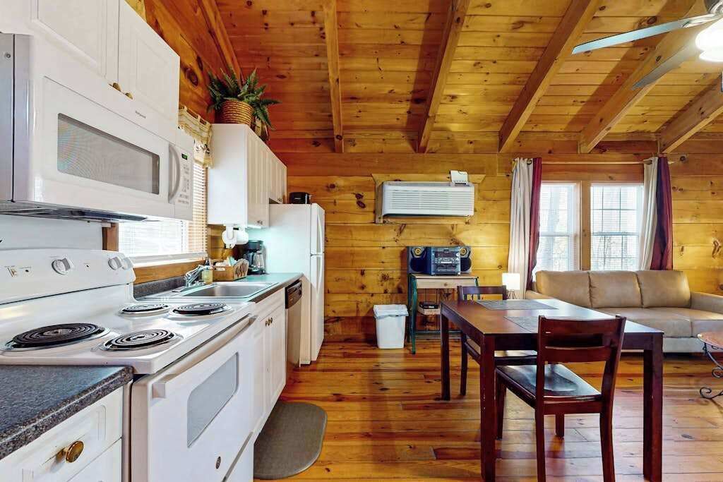 A cabin interior with a kitchen, dining area, and a sofa.