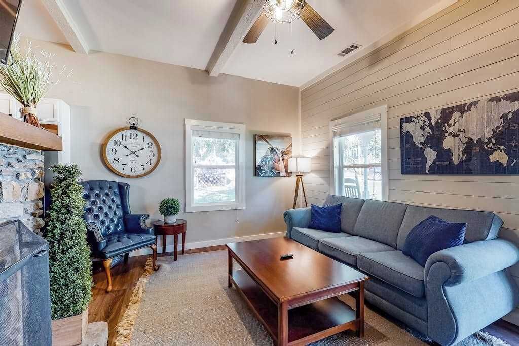 A living room with a fireplace, a blue armchair, a sofa, a coffee table, and a world map on the wall.
