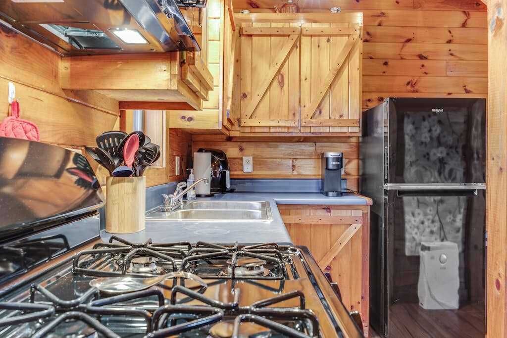 A compact kitchen with wooden cabinets, a gas stove, a sink, and a refrigerator.