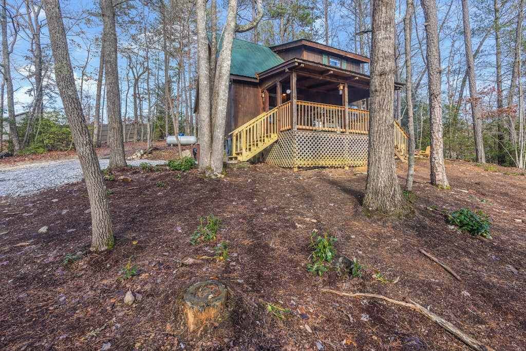 Una baita con una veranda di legno, circondata da alberi.