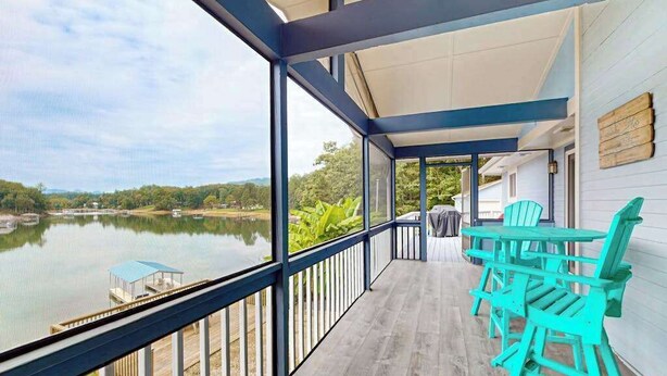 Un espace extérieur abrité avec vue sur un lac, une table avec des chaises et une terrasse en bois.