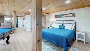 Une pièce avec une table de billard, un lit recouvert d’une courtepointe bleue et un panneau indiquant « VIE AU BORD DU LAC ».