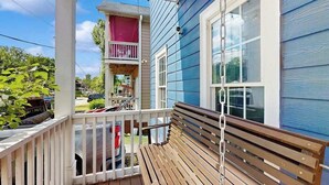Une terrasse en bois avec un banc, un espace porche couvert et une fenêtre avec des stores.