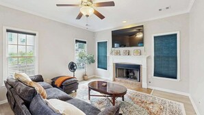 Un salon comprenant un canapé, une table basse, une cheminée et un ventilateur de plafond.