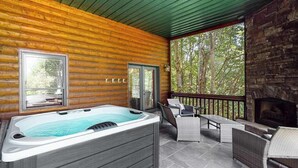 Uma cabana de madeira com hidromassagem, área de estar externa e lareira de pedra.