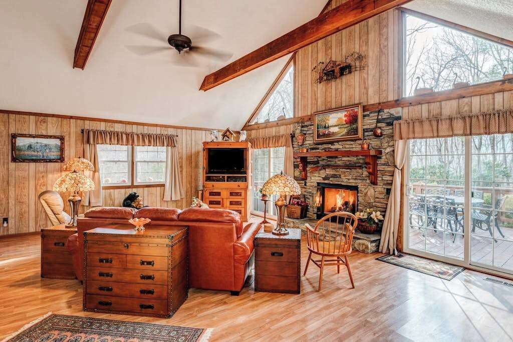 Ein geräumiges Wohnzimmer mit Holzböden, einem Kamin, einer Couch, einem Couchtisch und einer Steinsäule für den Kamin.