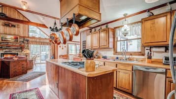 A spacious kitchen with wooden cabinets, a central island, and hanging pots.