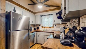 A compact kitchen with a stainless steel refrigerator, wooden countertops, and a window with a view. - White Pine Perch Stay (Clayton)