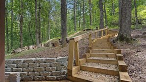 A wooden staircase leading up a stone wall in a forested area. - White Pine Perch Stay (Clayton)