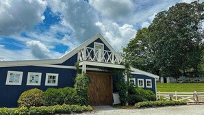 A blue building with a wooden door, white windows, and a white fence. - White Pine Perch Stay (Clayton)