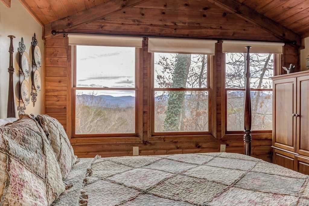 Une chambre avec un grand lit, des murs en bois et une vue sur l’extérieur.