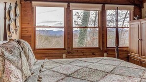 Una camera da letto con un letto grande, pareti in legno e vista sull'esterno.