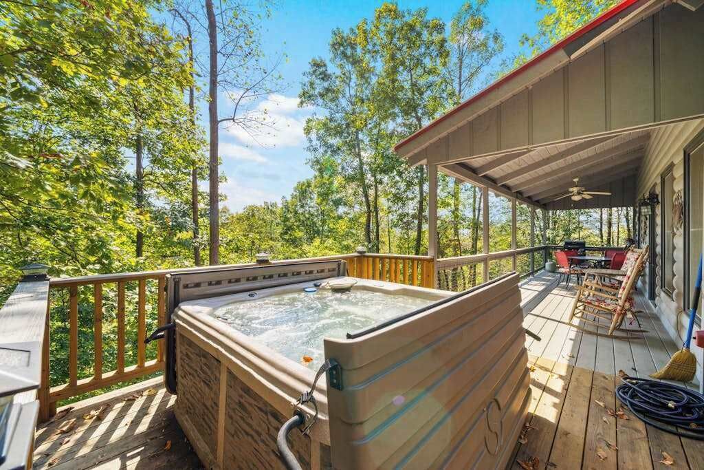 A hot tub on a wooden deck with a covered area and a view of trees.