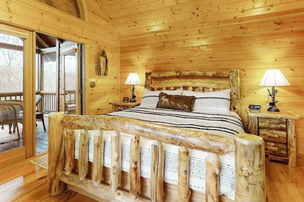 A wooden cabin bedroom with a bed, two bedside tables, and a window.