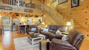 A cozy cabin interior with a living room, kitchen, and a staircase. - Copper Lantern Stays (Ellijay)