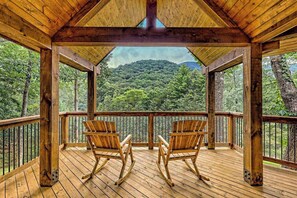 Eine Holzterrasse mit zwei Schaukelstühlen und Blick auf einen bewaldeten Berg.