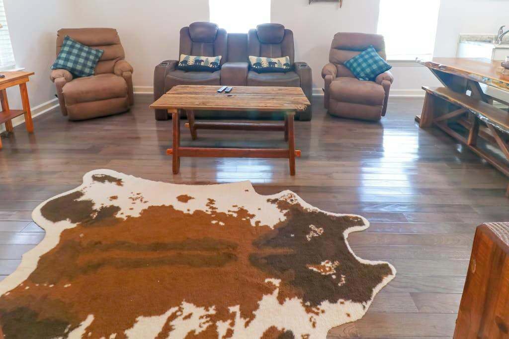 A living room with leather sofas, a wooden coffee table, and a large cowhide rug.