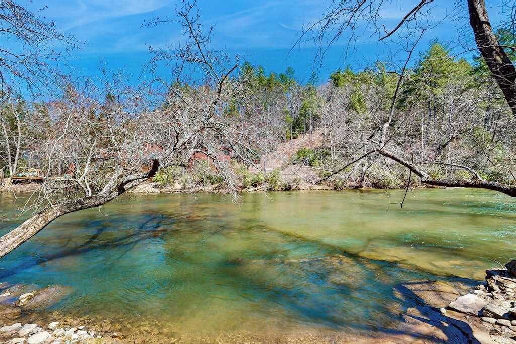 A clear river surrounded by trees and rocks.