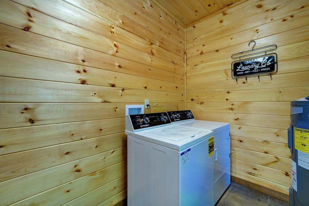 A laundry room with wooden walls, a washing machine, and a sign indicating laundry services.