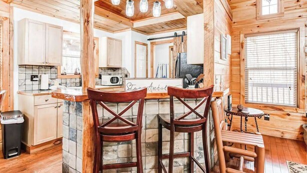 A rustic cabin interior with a kitchen, bar area, and seating. - Wooded Wonder Retreat (Cleveland)