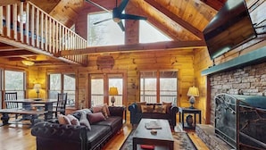 L’intérieur d’une cabane en rondins, avec une cheminée, un plancher en bois et une mezzanine.