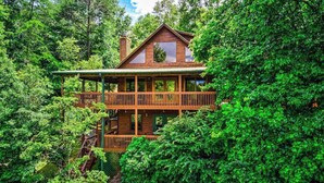 Une cabane en bois dotée d’un balcon, entourée d’une forêt dense.
