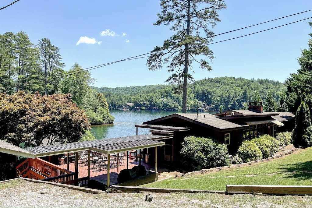 A lakeside lodge with a covered deck, a boat dock, and a view of the lake and forest.
